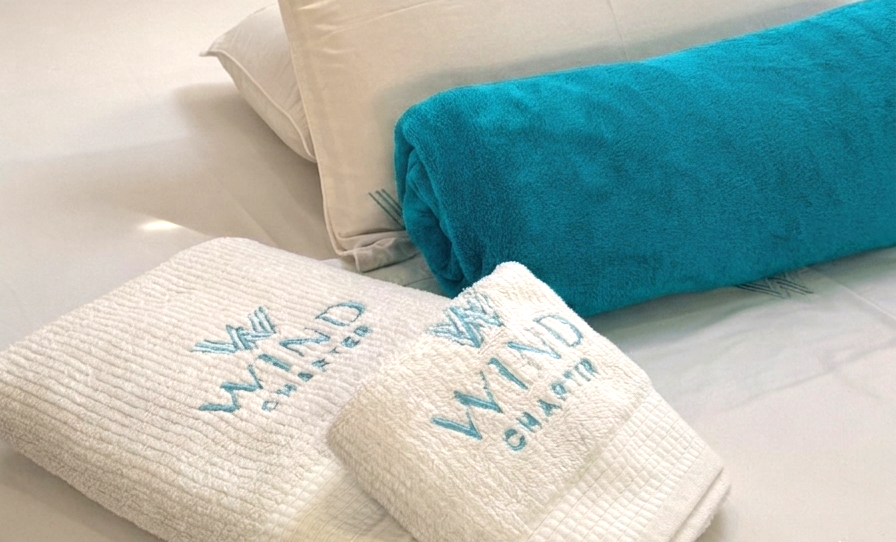 Cama perfeitamente organizada com toalhas bordados Wind charter