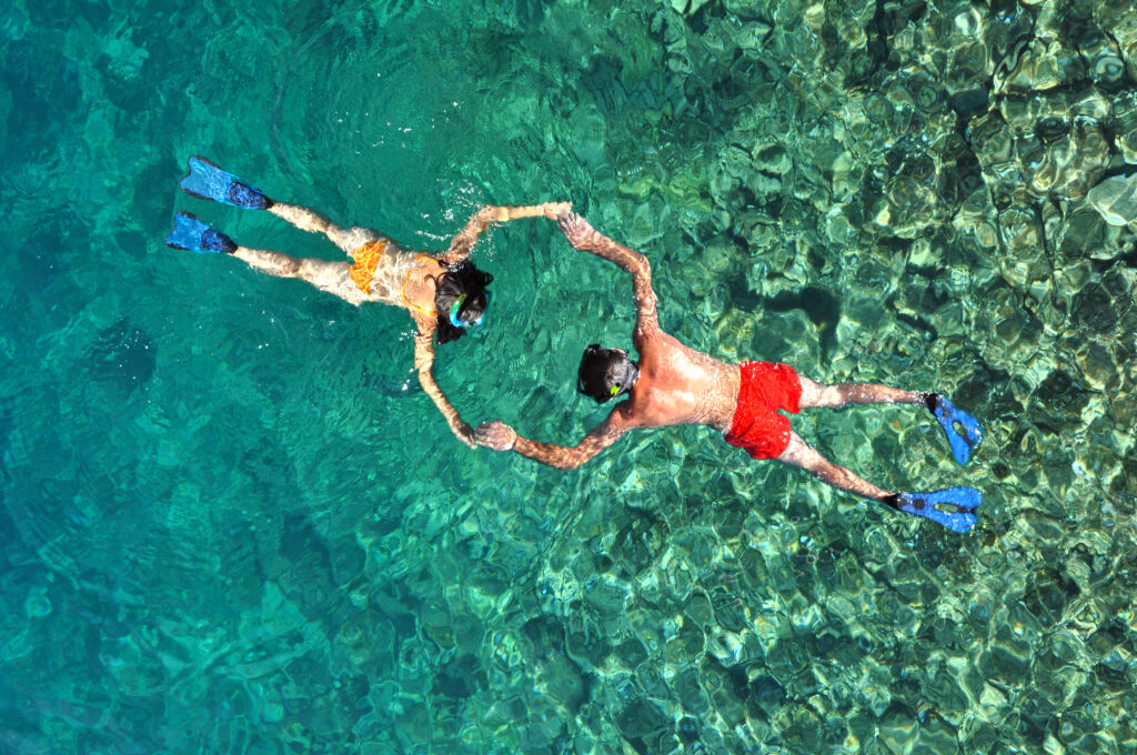 Casal faendo mergulho de snorkel em agua cristalina