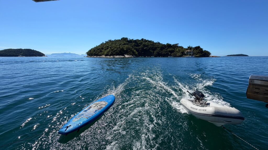 Barco e prancha de StandUp sendo puxados pelo barco no mar de Paraty-Rj