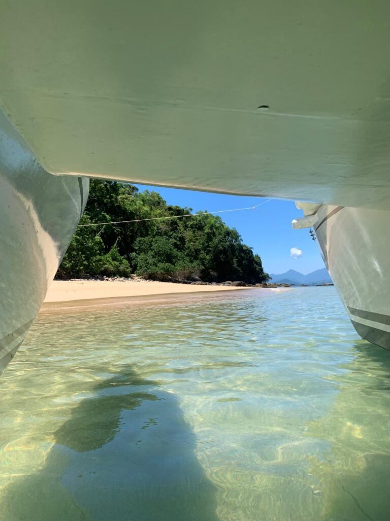 Catamaran fundeado em praia deserta com água cristalina